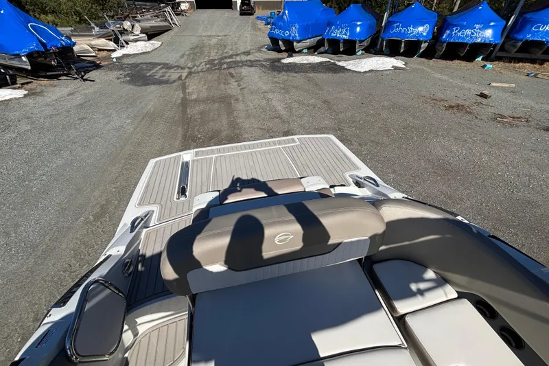 Slide: The Image of 2026 Crownline 278 SS boat with beige seating, parked on a gravel path near covered boats. - 13