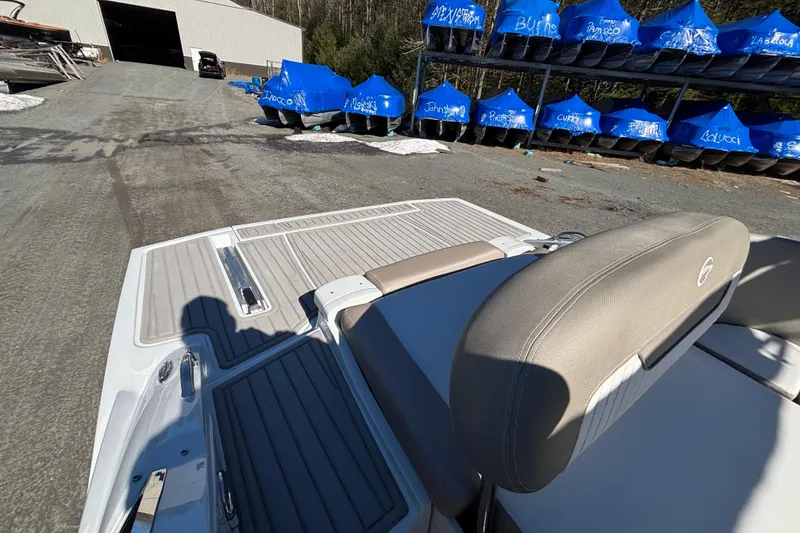 Slide: The Image of 2026 Crownline 278 SS boat with beige seating, parked near blue-covered boats. - 14