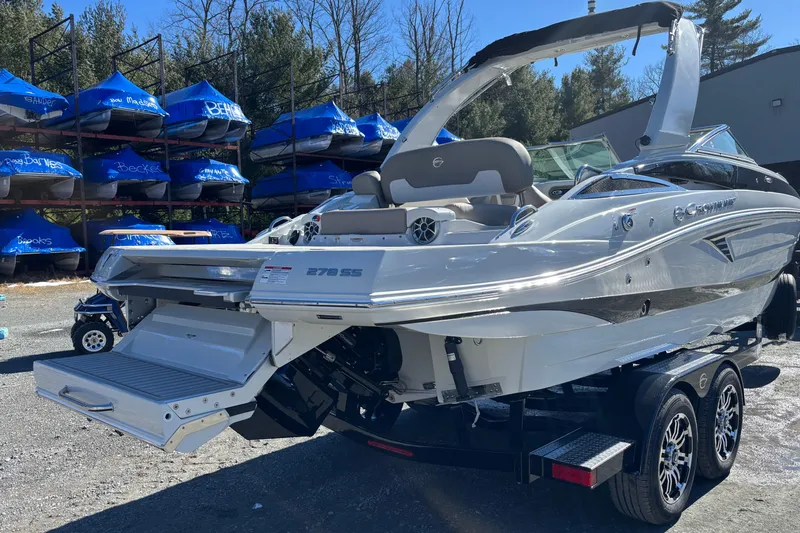 Slide: The Image of 2026 Crownline 278 SS boat on trailer, parked outdoors with covered boats in background. - 20