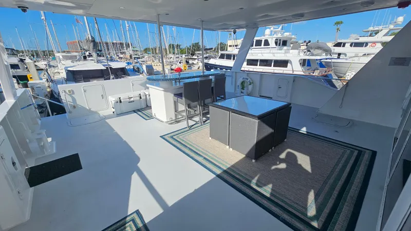 Slide: The Image of Spacious deck of 2009 Custom Flybridge Motoryacht in marina, featuring outdoor seating and table. - 45