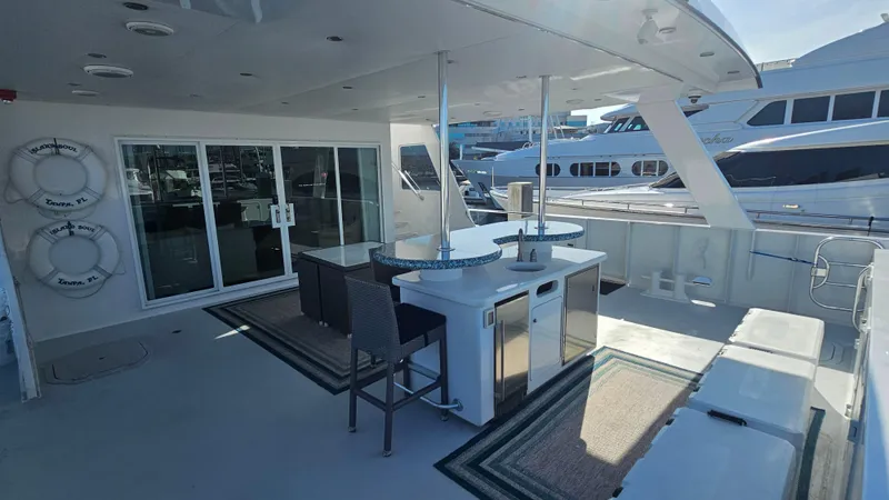 Slide: The Image of Luxurious 2009 Custom Flybridge Motoryacht deck with seating, bar, and marina view. - 47