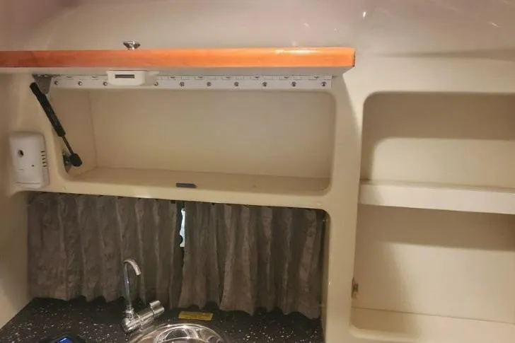 Slide: The Image of 2008 Formula 310 Bowrider interior with sink, storage, and curtains. - 33