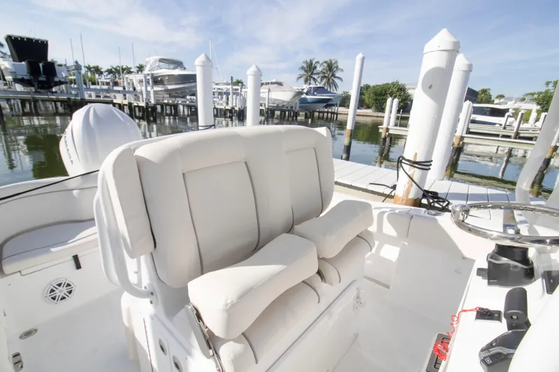 Slide: The Image of 2026 Sea Hunt Ultra 245 SE boat interior at marina, featuring plush seating and steering console. - 8