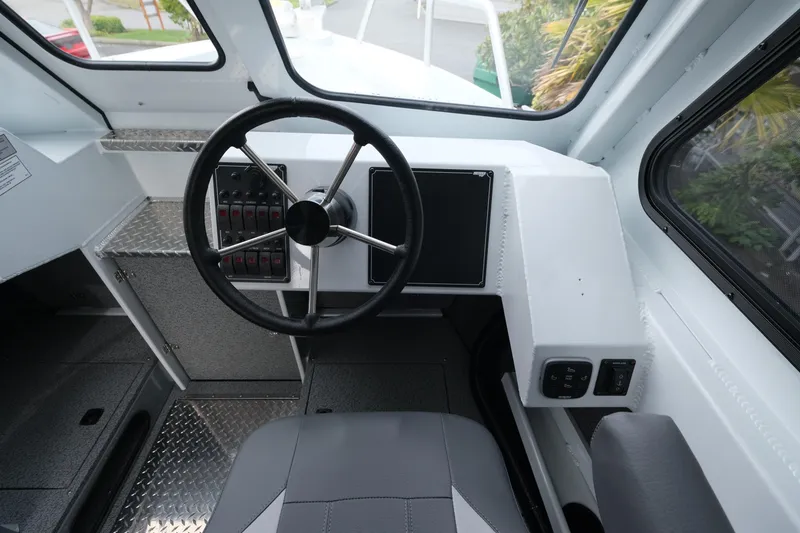 Slide: The Image of Interior view of 2025 Hewescraft 250 Alaskan boat cockpit with steering wheel and control panel. - 14