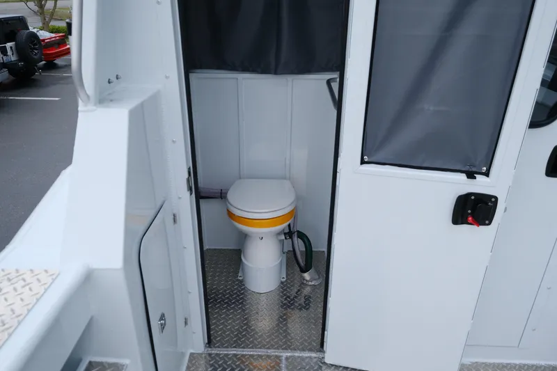 Slide: The Image of Interior of 2025 Hewescraft 250 Alaskan boat featuring a compact marine toilet. - 18