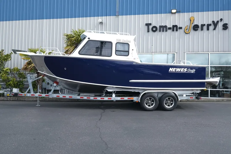 Slide: The Image of 2025 Hewescraft 250 Alaskan boat on trailer outside Tom-n-Jerry's store. - 2