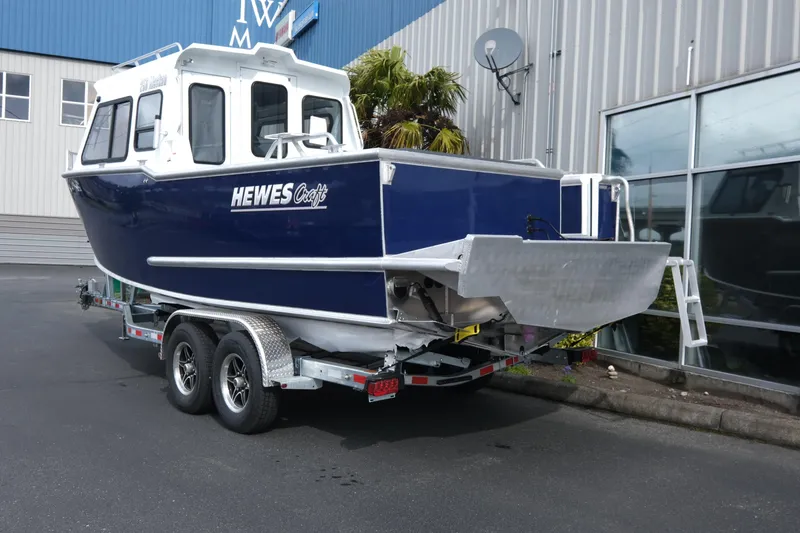 Slide: The Image of 2025 Hewescraft 250 Alaskan boat on trailer, parked outside industrial building. - 4