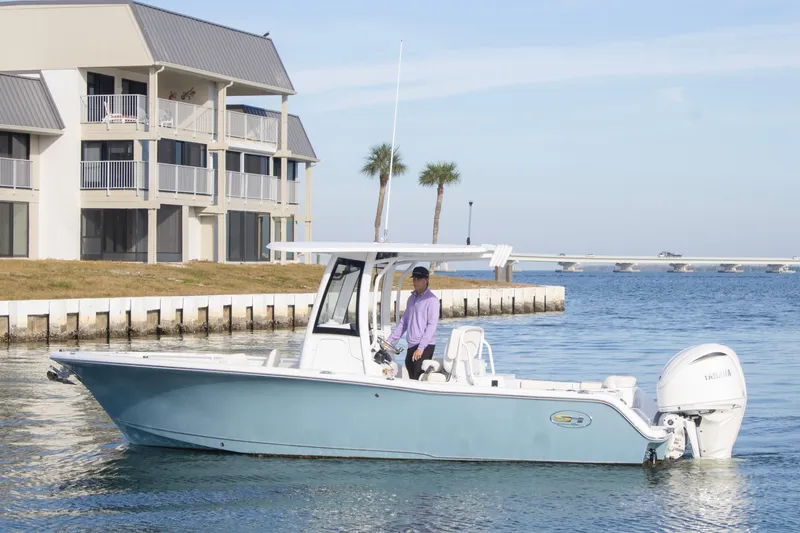 The Image of 2026 Sea Hunt Ultra 245 SE boat cruising near waterfront buildings. - 0