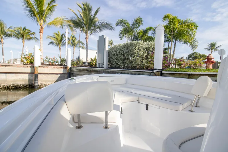 Slide: The Image of 2026 Sea Hunt Ultra 245 SE boat interior with white seating, docked near palm trees. - 11
