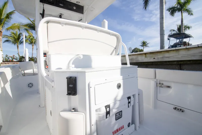 Slide: The Image of 2026 Sea Hunt Ultra 245 SE boat interior with seating and storage, surrounded by palm trees. - 6