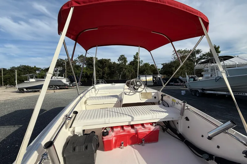Slide: The Image of 2017 Boston Whaler 150 Super Sport boat with red canopy and white seating. - 5