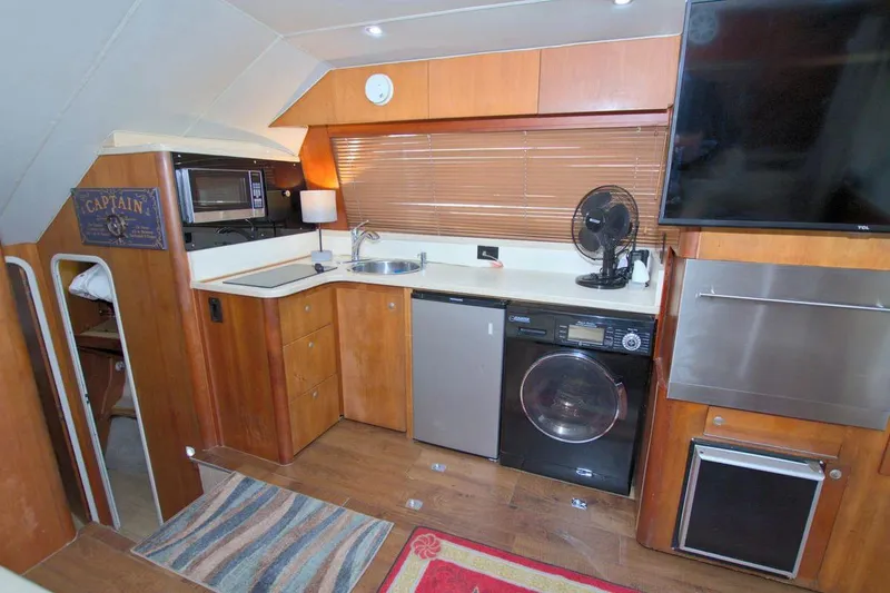 Slide: The Image of 1998 Luhrs 36 Convertible yacht interior with kitchen, appliances, and wooden cabinetry. - 31