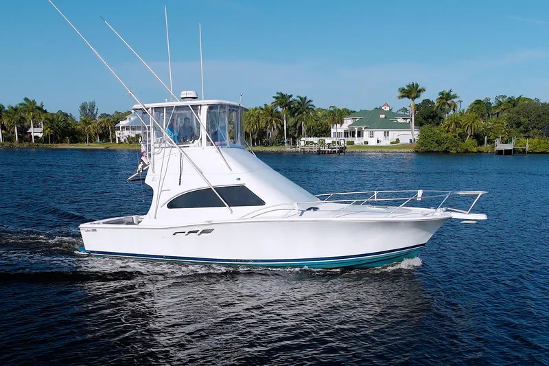 Slide: The Image of 1998 Luhrs 36 Convertible yacht cruising on a scenic waterway with palm trees. - 74