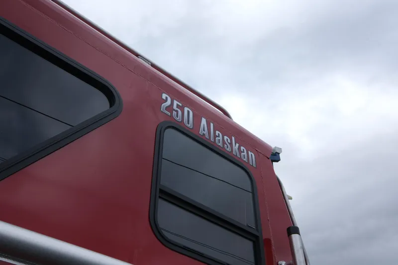 Slide: The Image of 2025 Hewescraft 250 Alaskan boat exterior with windows against cloudy sky. - 4