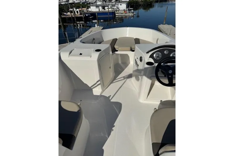Slide: The Image of 2018 Bayliner Element E21 boat interior with seating and steering wheel, docked by the water. - 18