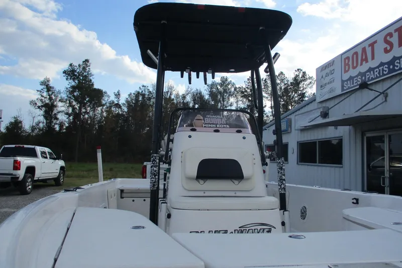 Slide: The Image of 2019 Blue Wave 2200 SL BAY boat at dealership, rear view with T-top and console. - 8