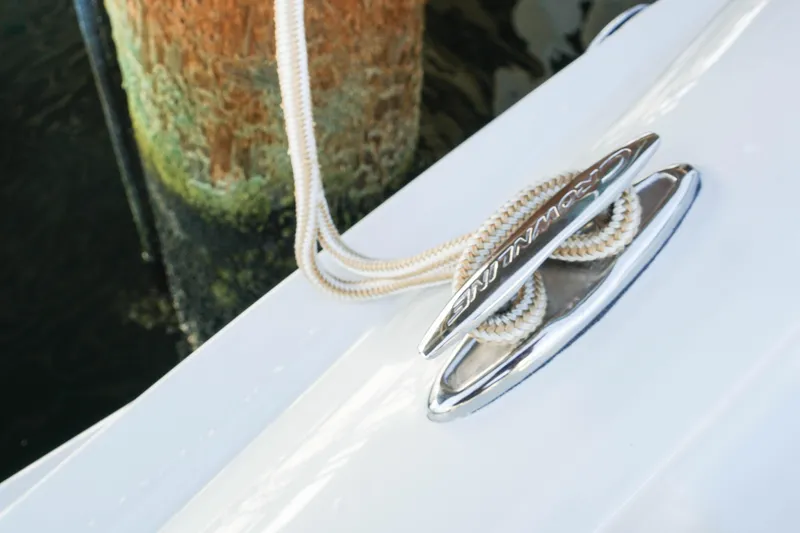 Slide: The Image of 2026 Crownline 288 SS boat cleat with rope, docked by a weathered post. - 16