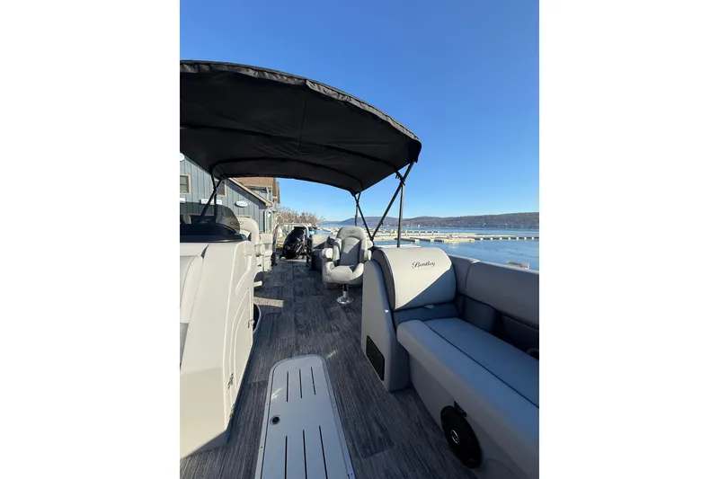Slide: The Image of 2026 Bentley Pontoons Legacy 243 Navigator interior with seating and canopy on a sunny day. - 12
