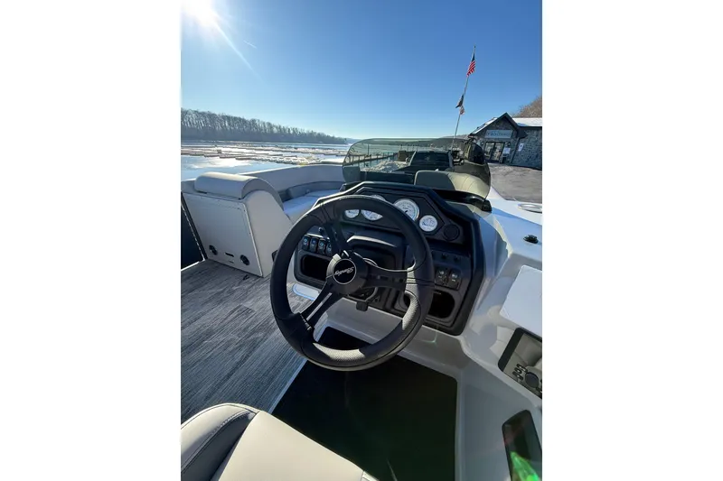 Slide: The Image of 2026 Bentley Pontoons Legacy 243 Navigator steering console with gauges, under clear blue sky. - 3