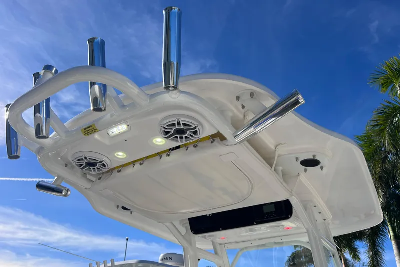 Slide: The Image of 2024 Everglades 243 Center Console boat with rod holders and speakers under a clear blue sky. - 44