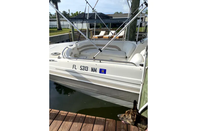 Slide: The Image of 2007 Hurricane SunDeck 237 OB boat docked, featuring white seating and registration number. - 2
