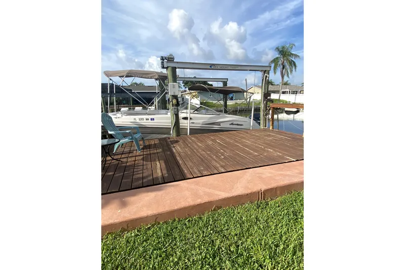 Slide: The Image of 2007 Hurricane SunDeck 237 OB boat docked beside wooden deck, under clear sky. - 6