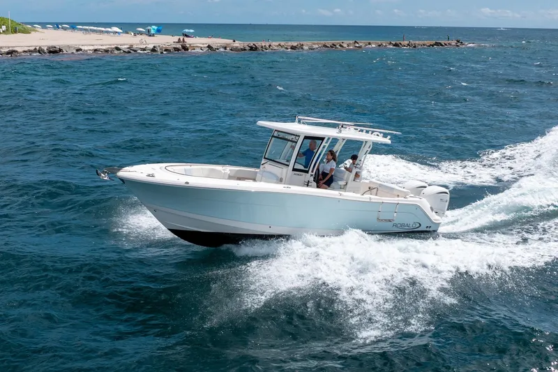 The Image of 2023 Robalo R302 Center Console boat cruising on ocean near rocky shoreline. - 0