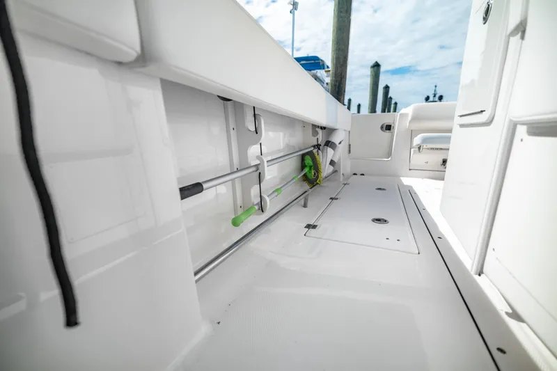 Slide: The Image of 2023 Robalo R302 Center Console boat interior with storage compartments and fishing rod holders. - 11