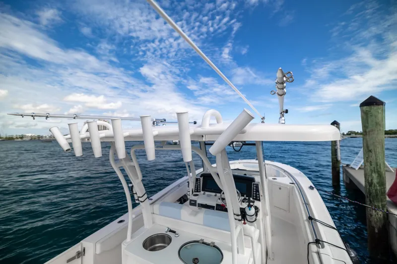 Slide: The Image of 2023 Robalo R302 Center Console boat docked, featuring fishing rod holders and navigation equipment. - 18