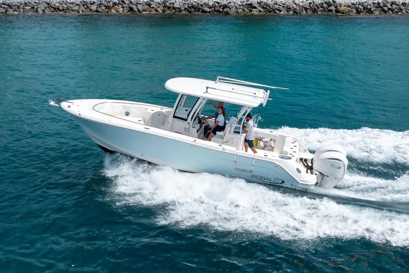 Slide: The Image of 2023 Robalo R302 Center Console boat cruising on clear blue water. - 2