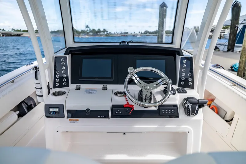 Slide: The Image of 2023 Robalo R302 Center Console boat helm with dual screens and steering wheel. - 21
