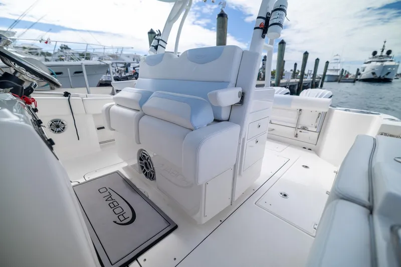 Slide: The Image of 2023 Robalo R302 Center Console boat interior with white seating and docked yachts in background. - 22