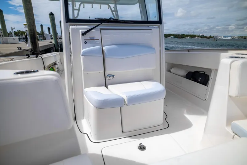Slide: The Image of 2023 Robalo R302 Center Console boat interior with white seating and storage compartments. - 25
