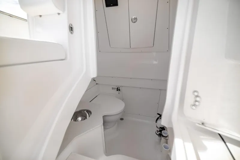 Slide: The Image of 2023 Robalo R302 Center Console boat interior with compact marine toilet. - 27