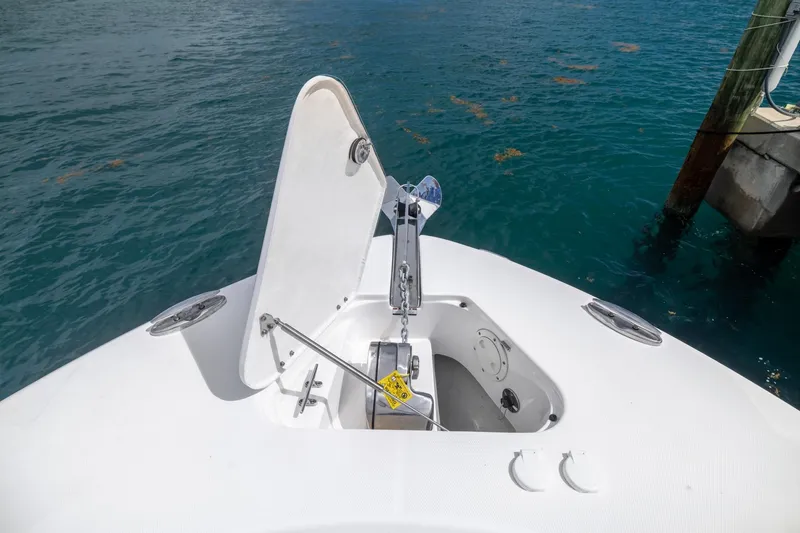 Slide: The Image of 2023 Robalo R302 Center Console boat anchor compartment open on calm water. - 34