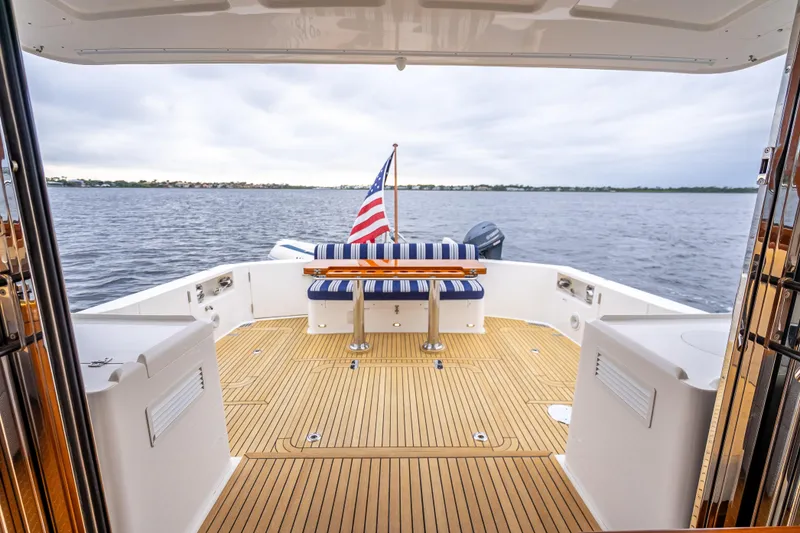 Slide: The Image of 2014 Grand Banks 50 Eastbay SX yacht deck with seating, table, and American flag. - 10