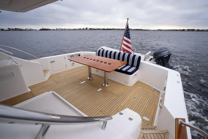 Slide: The Image of 2014 Grand Banks 50 Eastbay SX yacht deck with seating, table, and American flag. - 11