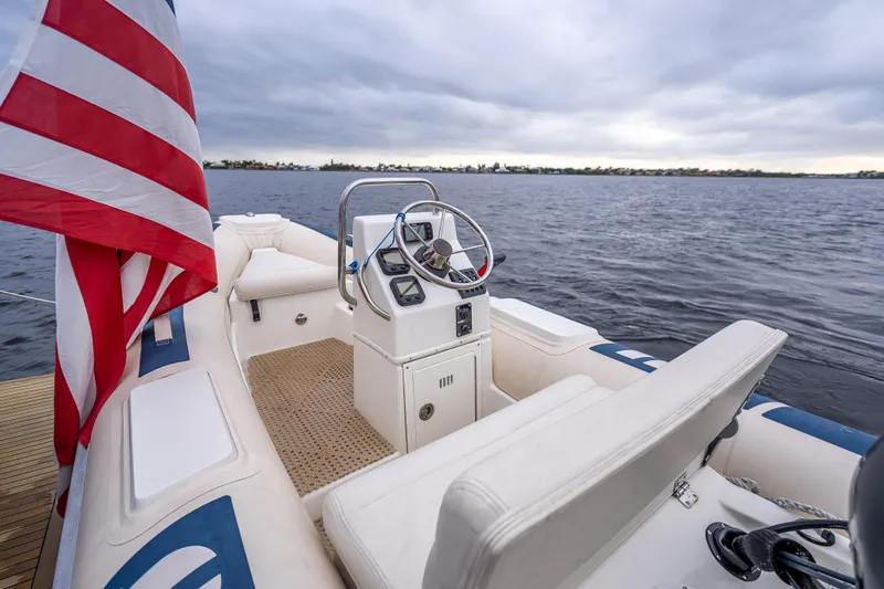 Slide: The Image of 2014 Grand Banks 50 Eastbay SX boat interior with steering wheel, American flag, and open water view. - 20