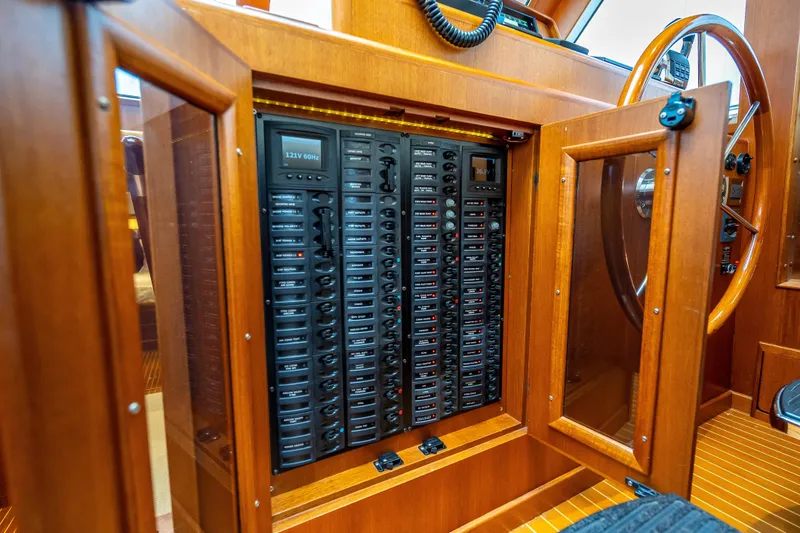 Slide: The Image of Electrical panel inside 2014 Grand Banks 50 Eastbay SX yacht, featuring wooden cabinetry. - 48