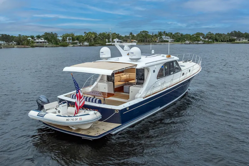 Slide: The Image of 2014 Grand Banks 50 Eastbay SX yacht on calm water, featuring a sleek design and American flag. - 5