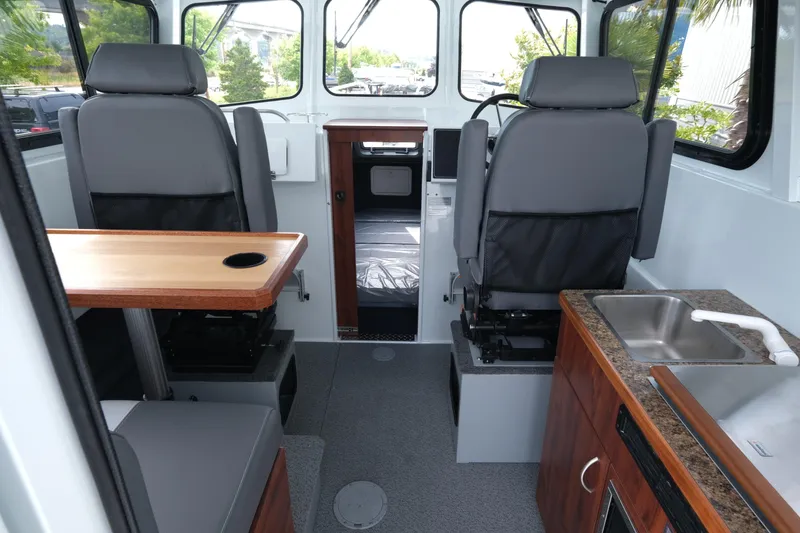 Slide: The Image of Interior of 2025 Hewescraft 240 Pacific Cruiser with seating, table, and kitchenette. - 10