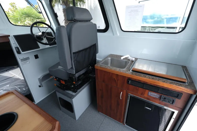 Slide: The Image of Interior of 2025 Hewescraft 240 Pacific Cruiser with helm, sink, and kitchenette. - 12