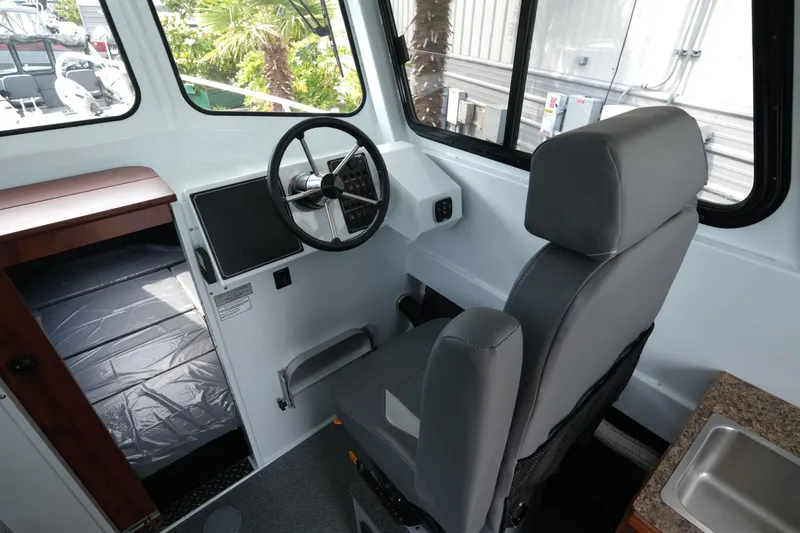 Slide: The Image of 2025 Hewescraft 240 Pacific Cruiser interior with steering wheel and captain's chair. - 13