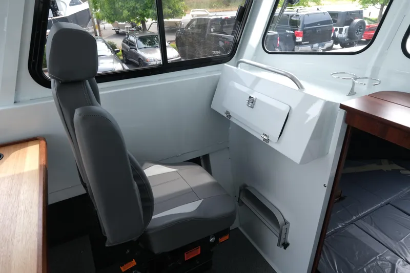 Slide: The Image of Interior of 2025 Hewescraft 240 Pacific Cruiser, featuring a comfortable gray seat and storage compartment. - 16