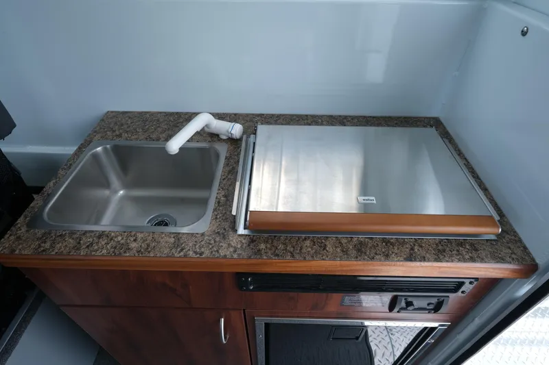 Slide: The Image of 2025 Hewescraft 240 Pacific Cruiser kitchen with sink and stainless steel countertop. - 18