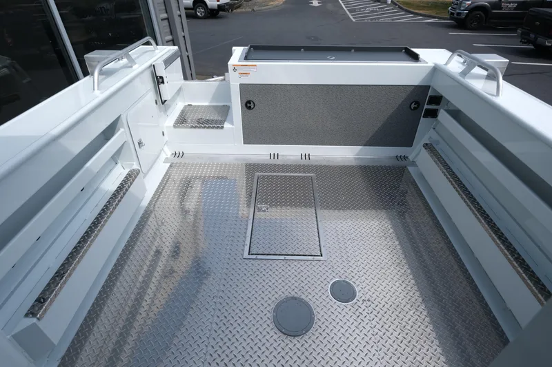 Slide: The Image of 2025 Hewescraft 240 Pacific Cruiser boat deck with diamond plate flooring and storage compartments. - 8
