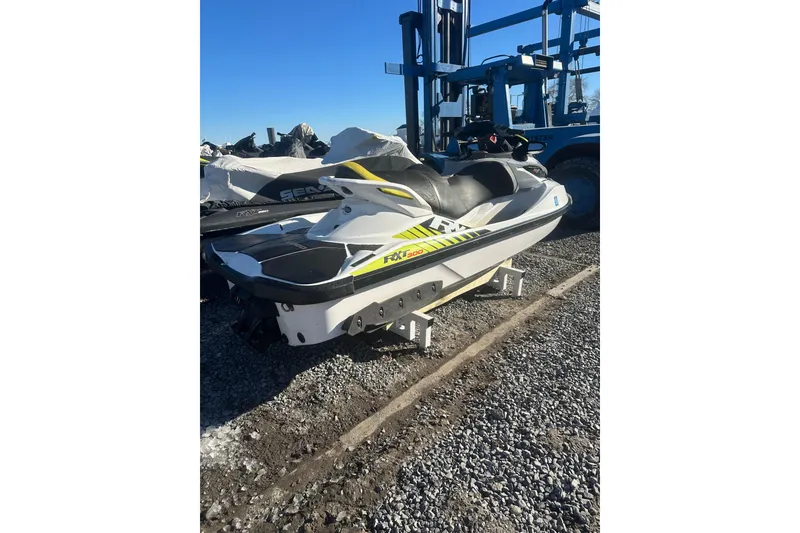 The Image of 2017 Sea-Doo RXT-X 300 jet ski on gravel, parked near industrial equipment. - 1
