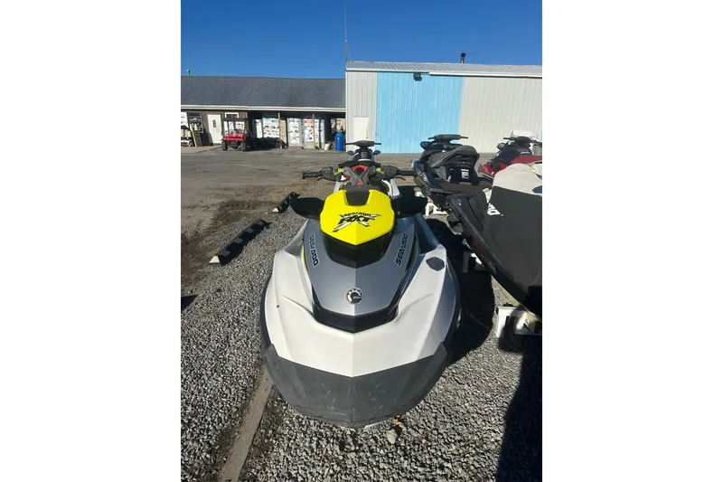 Slide: The Image of 2017 Sea-Doo RXT-X 300 jet ski parked on gravel near a building. - 2
