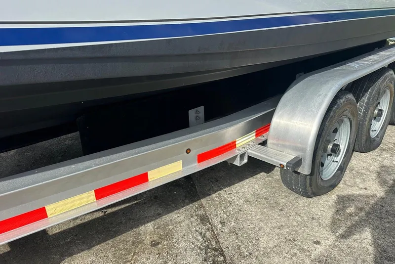Slide: The Image of Trailer for 2017 Cobia 296 Center Console boat, featuring dual axles and reflective tape. - 16