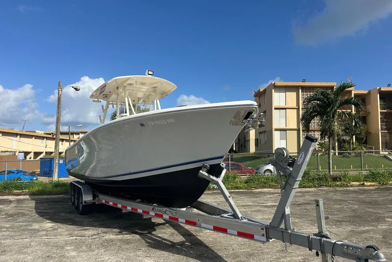 Slide: The Image of 2017 Cobia 296 Center Console boat on trailer, parked outdoors under blue sky. - 19